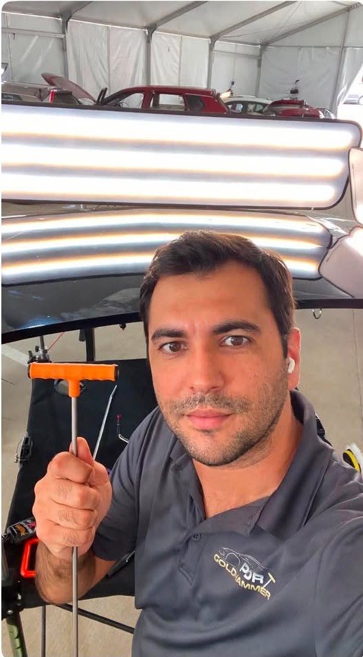 Marcus Gomes, paintless dent repair technician, at work with a reflection light board